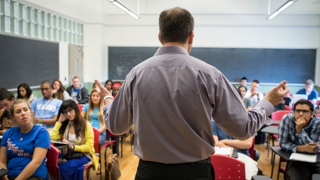 Back of male professor teaching infront of a classroom of students
