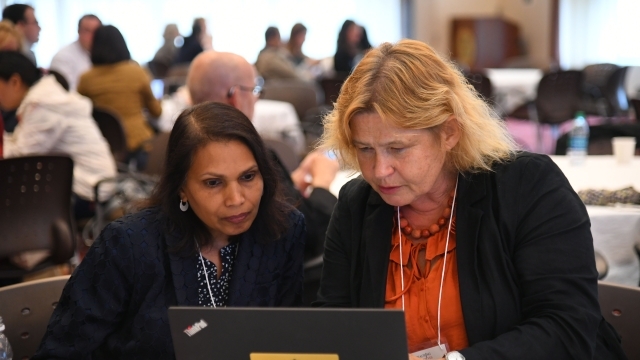 Two female faculty members looking at laptop screen 