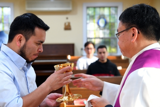 Father giving blood to participant during mass