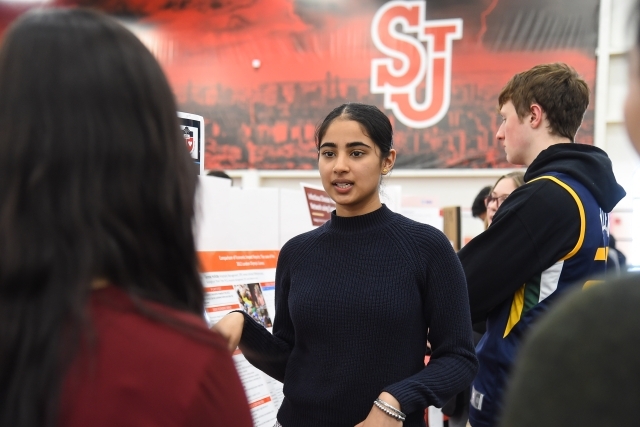 Female talking to group infront of research posters