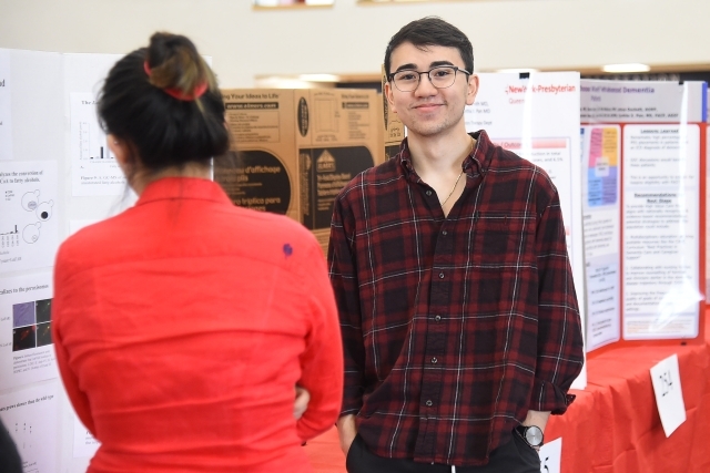 Male smiling at camera infront of research poster