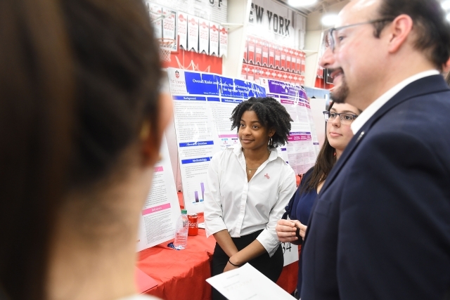 Group of students and administrators conversing infront of research posters