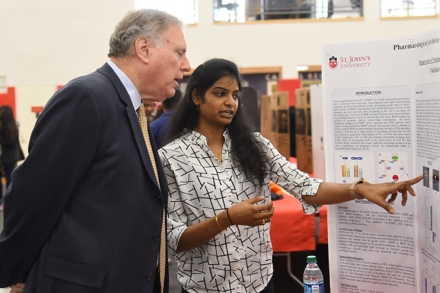 Female student pointing to poster board show Dean DiGate research