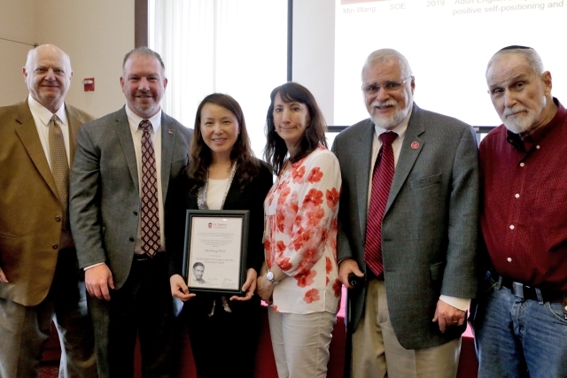 Female holding award with other University administrators