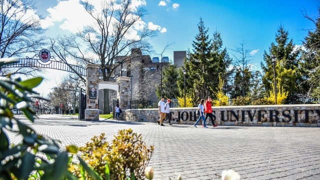 St. John's University front gate with students walking on/off campus