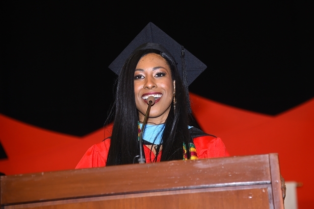 Female student speaking at podium in commencement attire