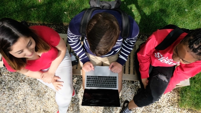 Overhead shot of three students looking at laptop