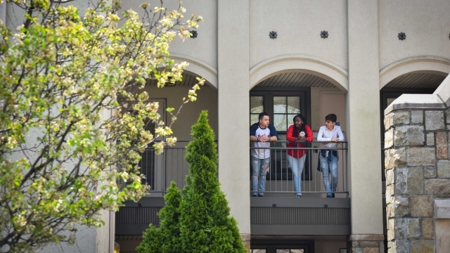Three students talking to one another on the balcony
