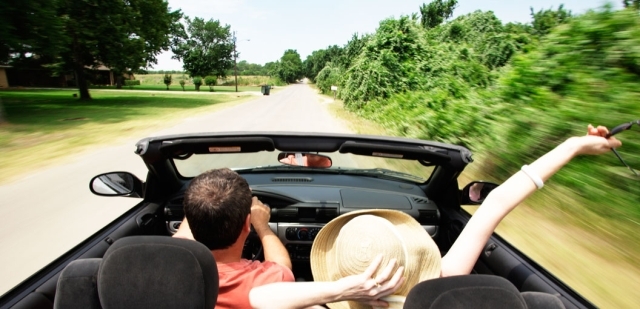 Male driving a car with a female passenger in a convertible