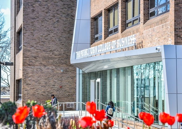 Exterior shot of The Peter J Tobin College of Business building with tulips blooming