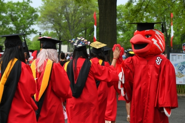 Johnny giving high fives to graduates at Commencement ceremony