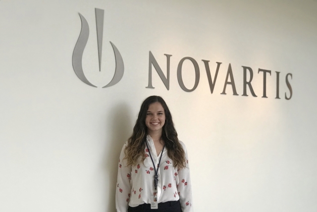 Jennifer Soffing standing infront of Novartis logo on the wall