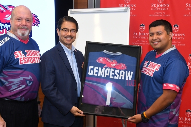eSports coach and team member handing President Gempesaw a framed Jersey