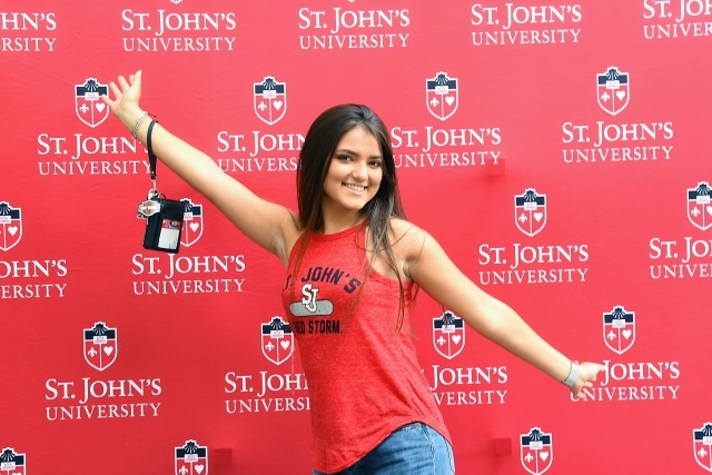 Female student posing in photo booth holding ID