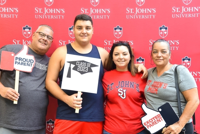 Family of 4 infront of step and repeat holding photo booth props
