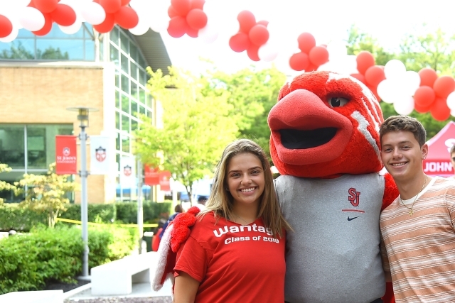 Johnny posing with two students infront of balloon arch