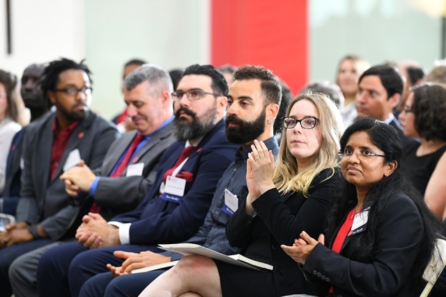Group of faculty members sitting in crowd looking at the stage