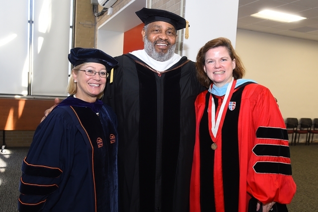 Three faculty members in rob smiling at camera