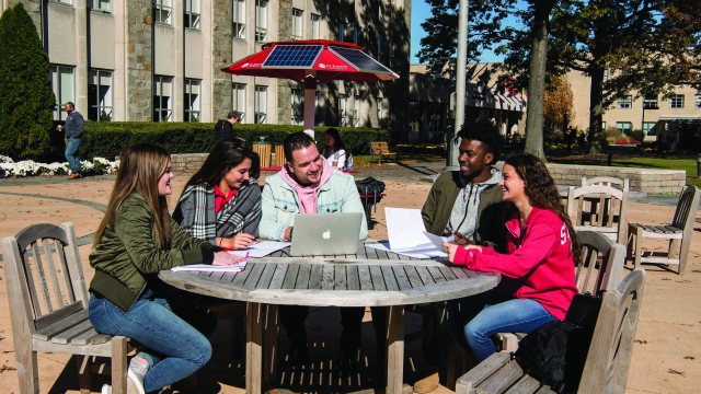 Students sitting at table outside talking 