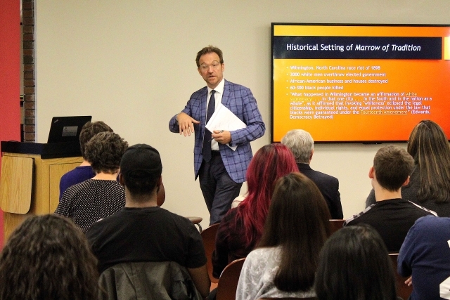 Dr Fanuzzi speaking at the podium infront of a powerpoint presentation