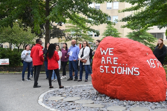 A campus tour group stopping by SJU red rock
