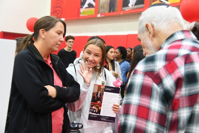 Guest waves at camera from Academic Fair