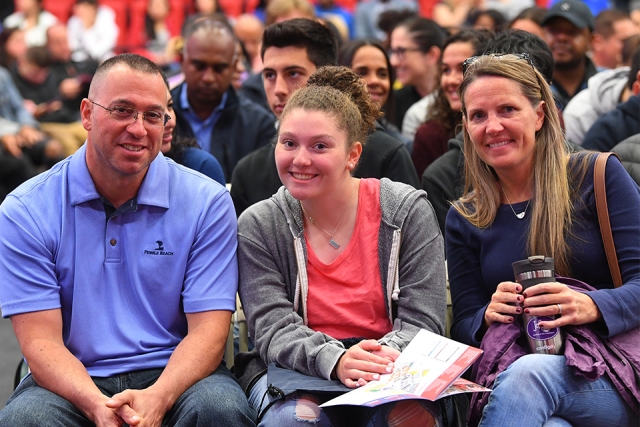 Guests looking up from event program to smile