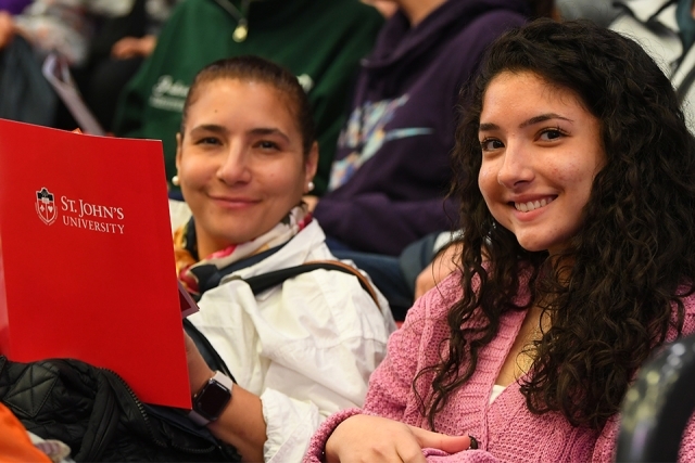 Guests looking up from red folder to smile for camera