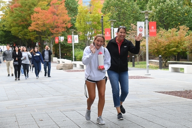Guests wave to camera while walking in Residence Village