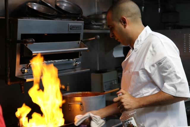 Male cooking on stove as pan flames up