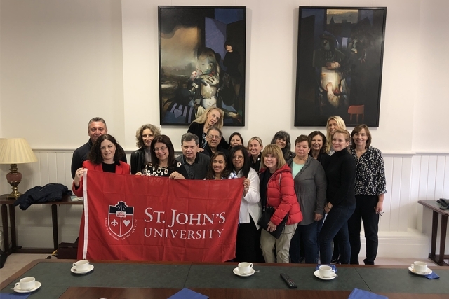 Alumni and friends holding up a St. John's banner