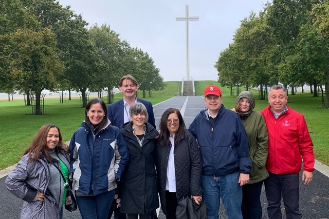 Alumni and Friends pose for a picture in front of an outdoor cross