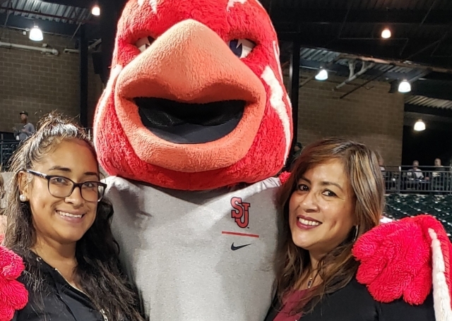 Johnny Thunderbird posing with two females in baseball stands