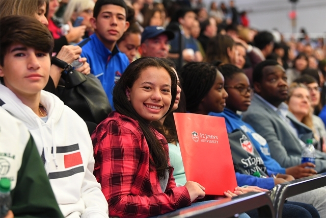 Smiling guest showing off red SJU folder