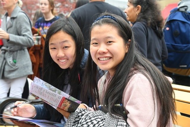 Students smile while looking at event program