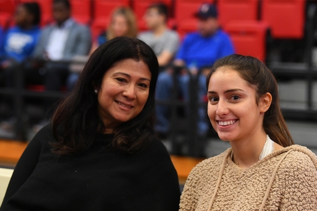 Two guests smile from their seats at welcome program