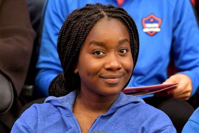 Welcome program guest smiling while holding SJU backpack