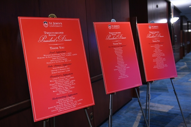 Three red poster boards on easels displaying lists of President's Dinner supporters