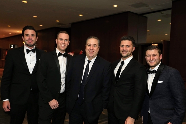 Guests in tuxedos pose for a picture in the hallway at the 2019 President’s Dinner