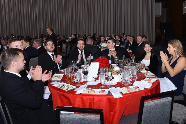 Seated guests at a table clapping
