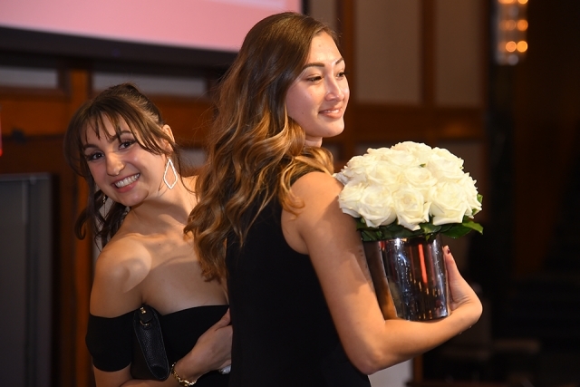 Two guests at the St. John’s University 2019 President’s Dinner, one holding a vase of white roses