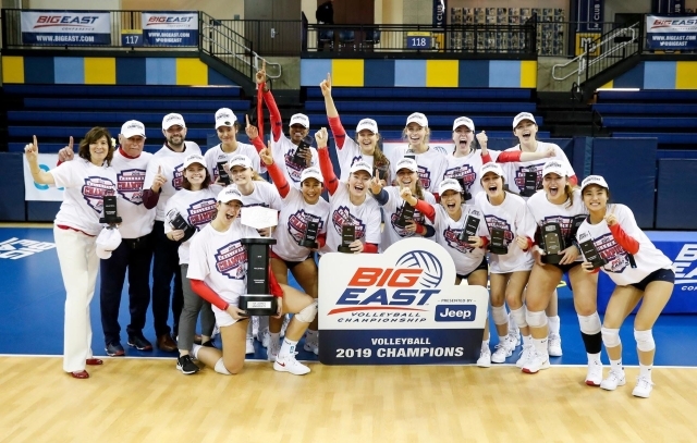 Women's volleyball team poses with big east championship sign