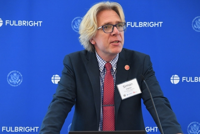 Simon Møller speaking at podium with Fulbright banner behind him