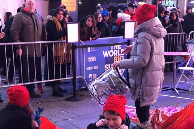 Woman standing holding a bag in front of barricade in Times Square
