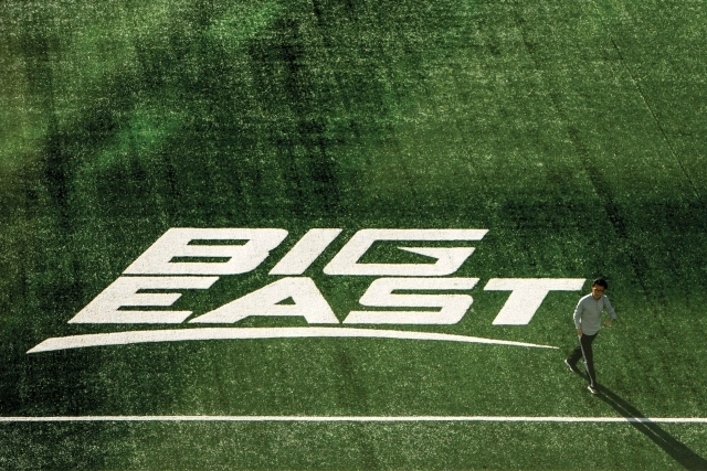 Student walking across field with BIG EAST painted on field