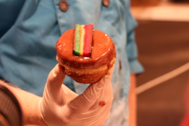 Rainbow donut being held by baker