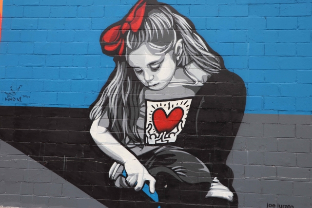 Mural of girl drawing on the sidewalk with chalk