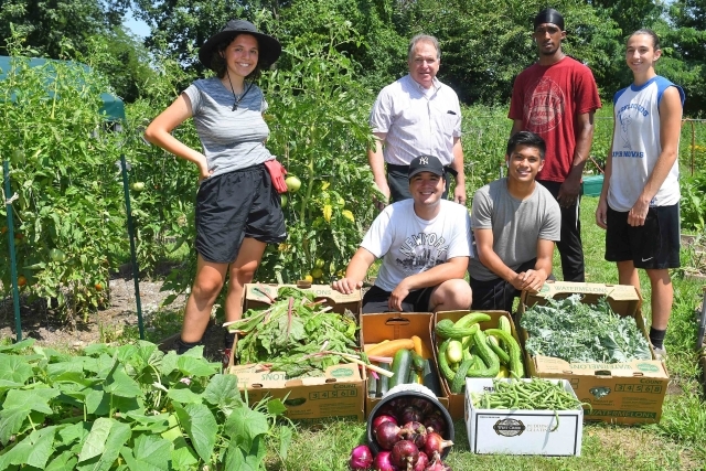 Students and Faculty posing for photo in the middle of campus organic garden