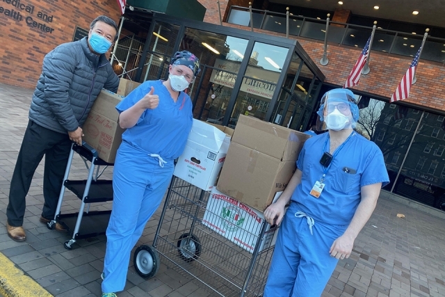Healthcare workers standing with boxes of donated food 