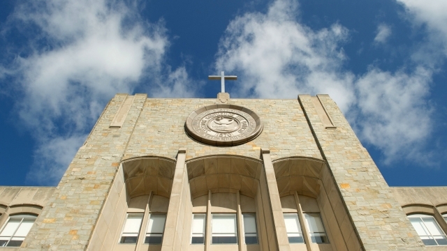 Top of St. Augustine Building featuring cross and St. John's University Seal